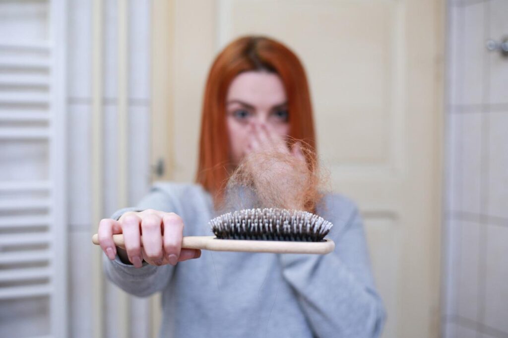 mulher com o cabelo caindo na escova