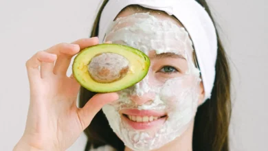 imagem de uma mulher com um abacate na mão e uma mascara de hidratação no rosto